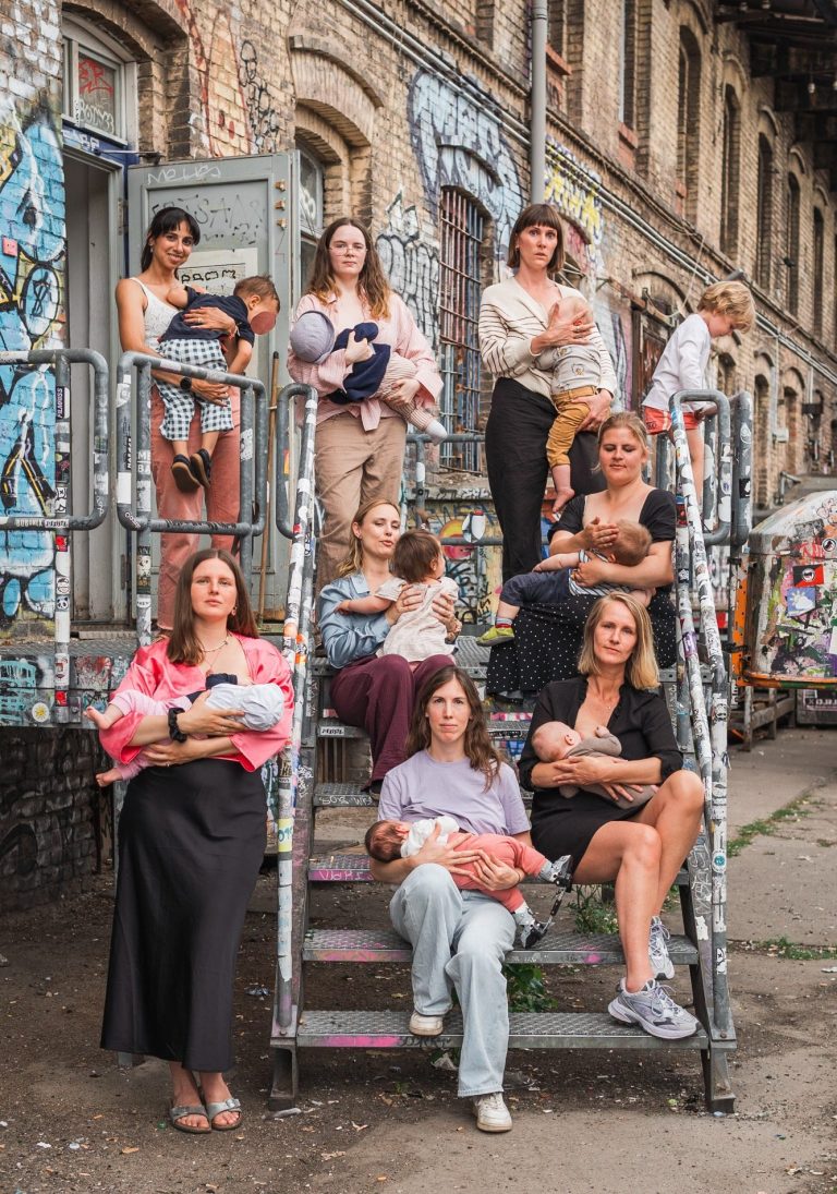 Die Aktion #IchStillWoIchWill macht Stillen im öffentlichem Raum sichtbar Eine Gruppe von Frauen auf einer Treppe, die nebeneinander ihre Babys und Kleinkinder stillen und selbstbewusst in die Kamera schauen.